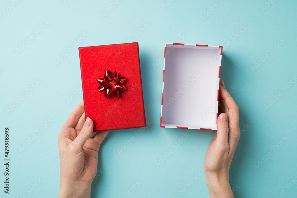 First person top view photo of st valentine's day decorations young woman's hands holding open empty giftbox with red lid and star bow on isolated pastel blue background with empty space First person top view photo of st valentine's day decorations young woman's hands holding open empty giftbox with red lid and star bow on isolated pastel blue background with empty space