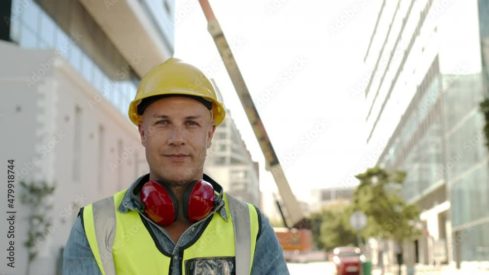 Video portrait of a manual worker looking at the camera while standing at a construction site. Mature man wearing protective workwear while working at a construction site.
