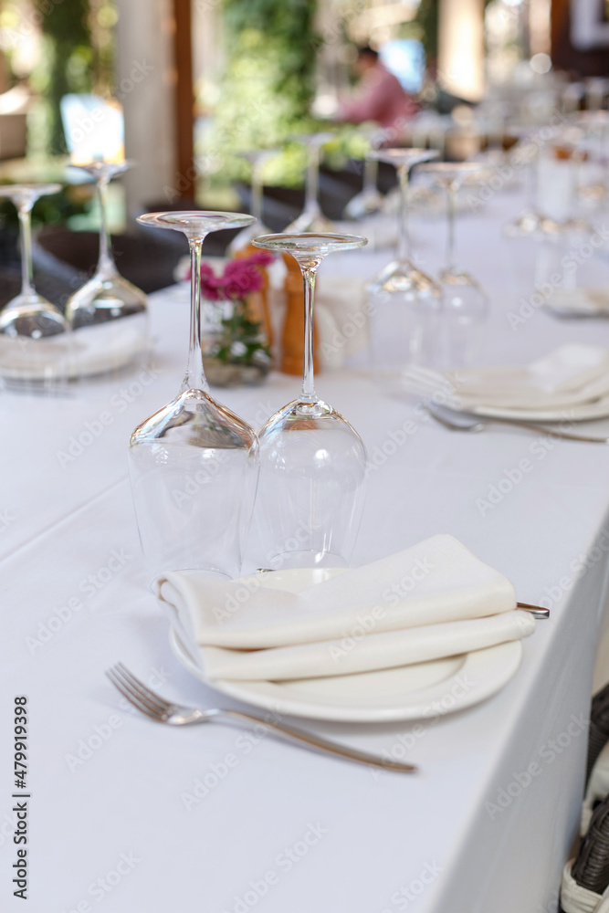 Tables set for meal. Plate, wine glasses and cutlery on a banquet server table with a white tablecloth in a luxury restaurant Tables set for meal. Plate, wine glasses and cutlery on a banquet server table with a white tablecloth in a luxury restaurant