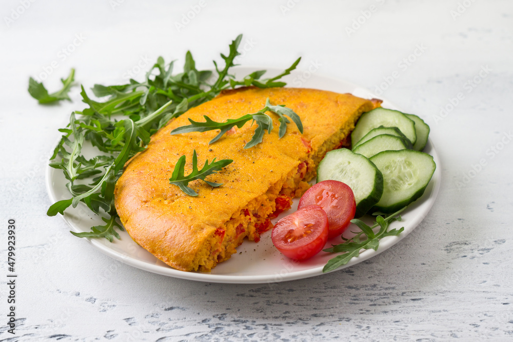 Vegan chickpea omelet with bell peppers served with tomatoes, cucumbers, lettuce and parsley on light gray textured background. Healthy homemade food Vegan chickpea omelet with bell peppers served with tomatoes, cucumbers, lettuce and parsley on light gray textured background. Healthy homemade food