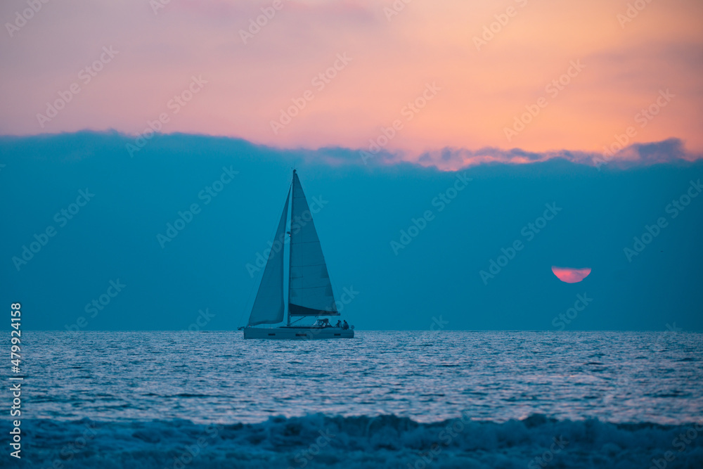 Yacht sailing in the sunrise time. Sea landscape view with a beautiful sailboat. Yachting tourism sea voyage on the sail boat. Romantic trip on the sail vessel.