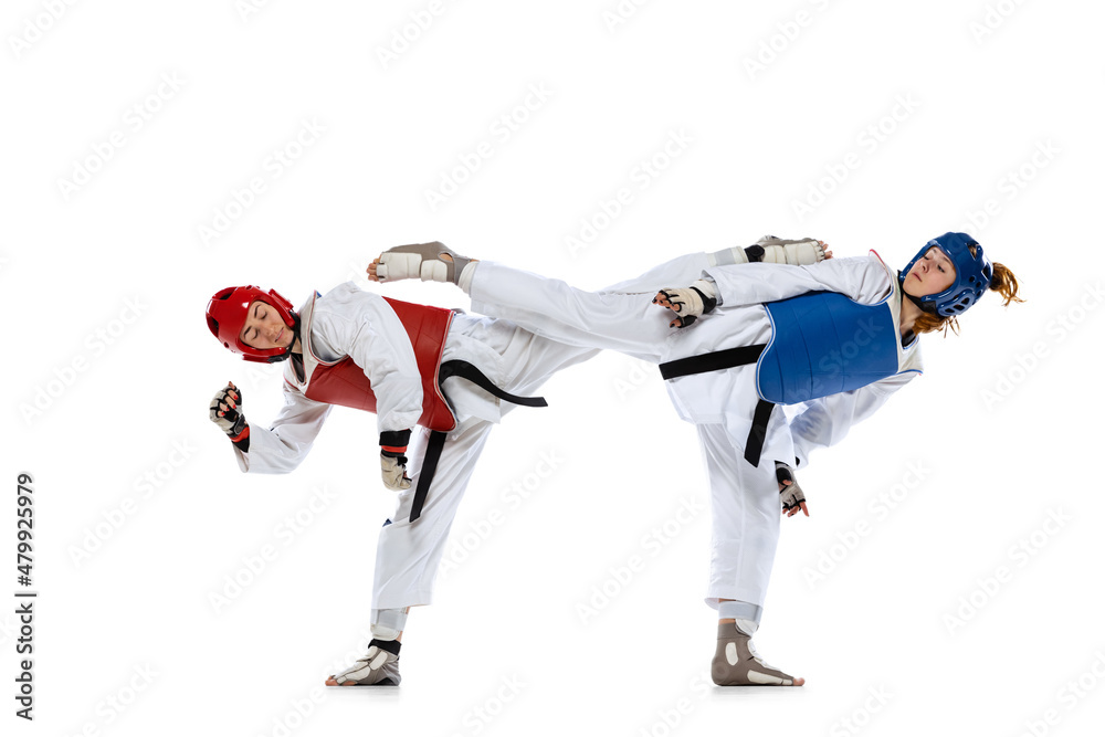 Portrait of two young women, taekwondo athletes practicing, fighting isolated over white background. Concept of sport, skills