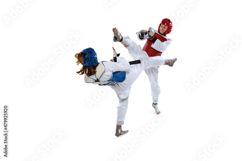 Fototapeta Naklejka Na Ścianę i Meble -  Portrait of two young women, taekwondo athletes practicing, fighting isolated over white background. Concept of sport, skills