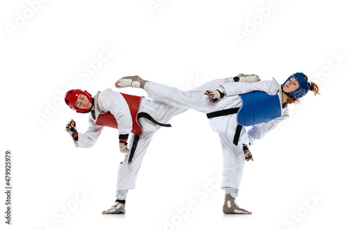 Portrait of two young women, taekwondo athletes practicing, fighting isolated over white background. Concept of sport, skills