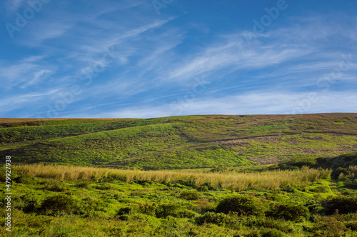 picture of a hill with clouds and blue sky  picture of a hill with blue sky in the background