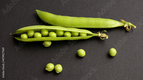 Peas in pod isolated on black background, on table. Fresh pea seeds. Close up. 