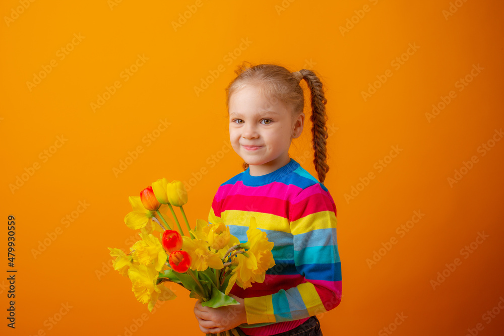 a cute little girl in a multicolored sweater holds a bouquet of spring flowers on a yellow background a cute little girl in a multicolored sweater holds a bouquet of spring flowers on a yellow background