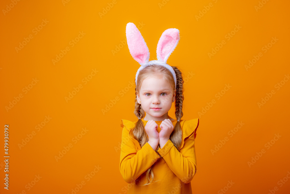 cute little girl with Easter bunny ears,on a yellow background, shows different emotions, joy, surprise, happiness, dreaming,