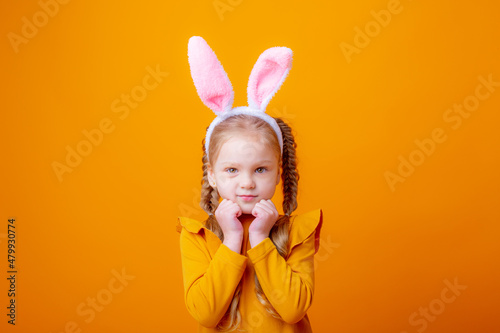 cute little girl with Easter bunny ears,on a yellow background, shows different emotions, joy, surprise, happiness, dreaming,