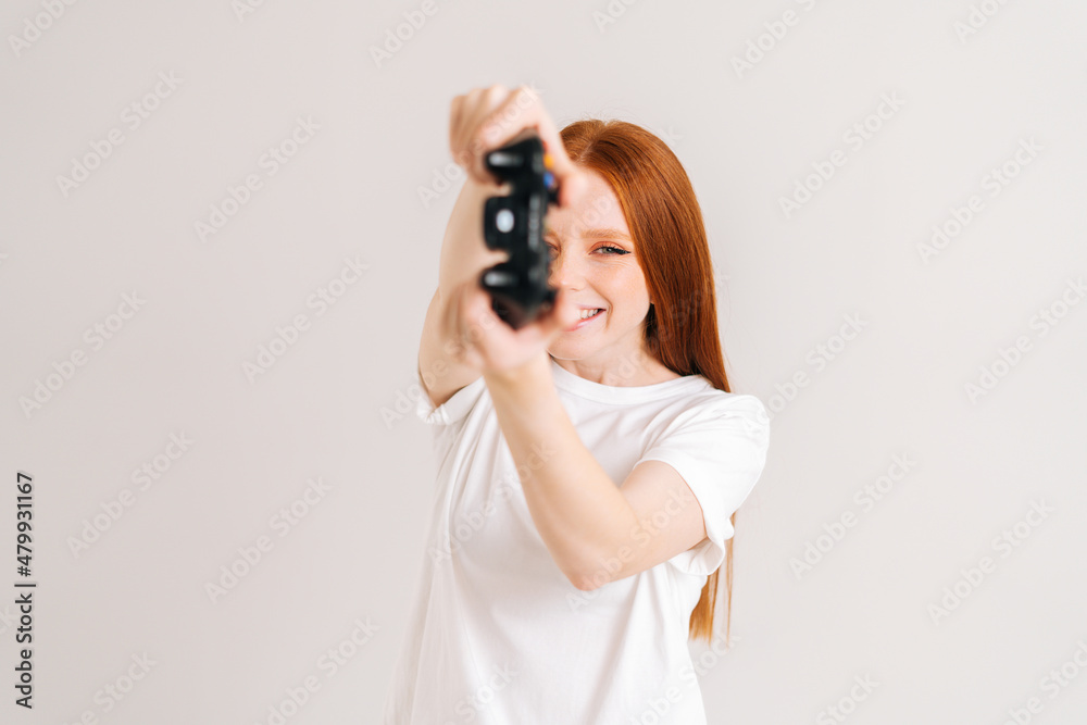 Studio portrait of joyful pretty young woman playing video game with controller looking at camera on white isolated background. Happy lady using joystick on console enjoying online game. Studio portrait of joyful pretty young woman playing video game with controller looking at camera on white isolated background. Happy lady using joystick on console enjoying online game.