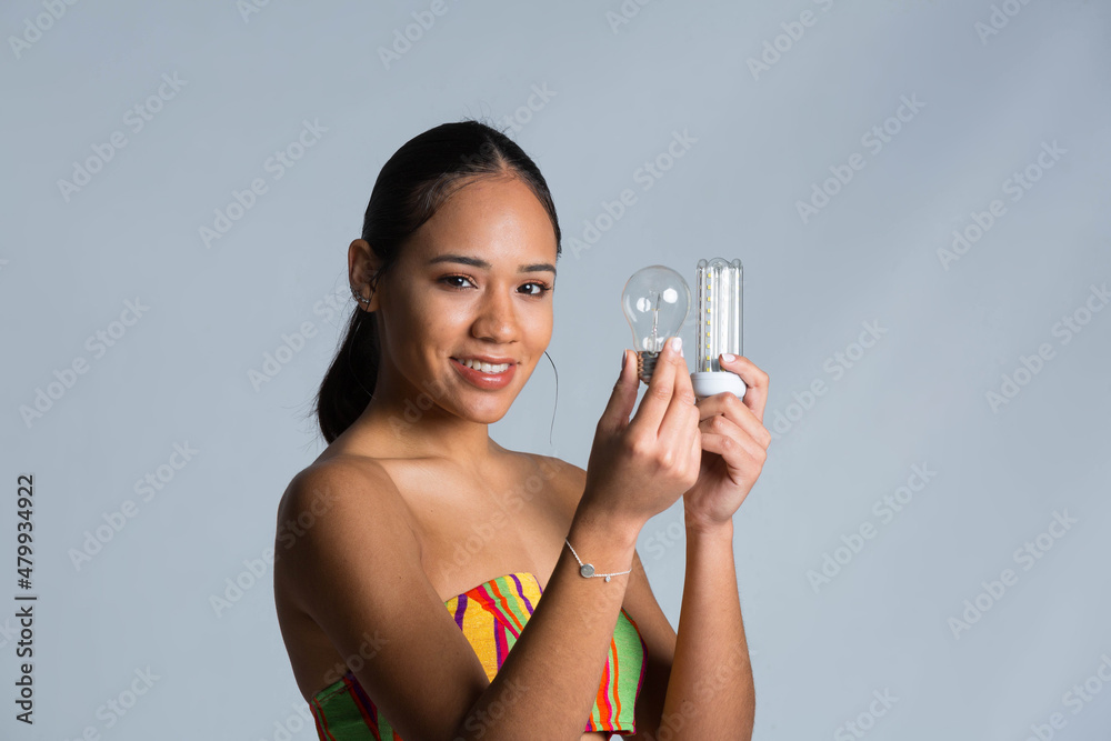 young girl with light bulb in her man with low and high power consumption young girl with light bulb in her man with low and high power consumption