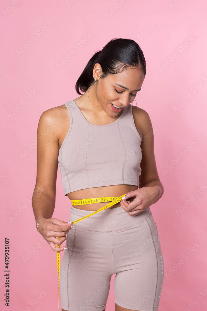 Young girl taking her measurements with a tape measure Young girl taking her measurements with a tape measure