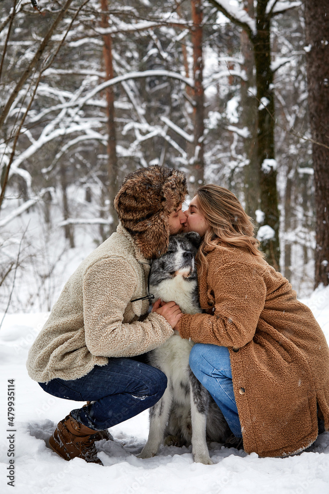 Married young couple on a walk in the winter forest with a pet dog husky