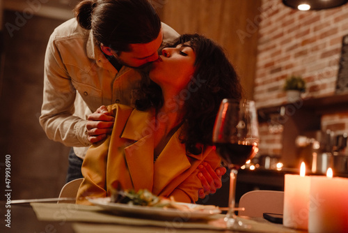 White couple kissing and hugging while having romantic dinner at home
