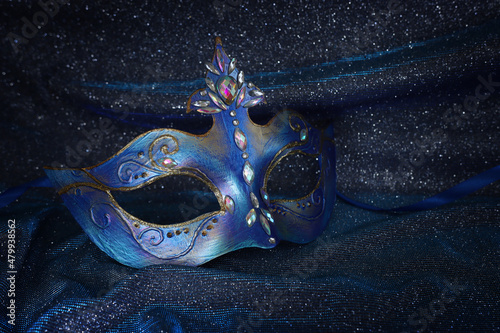 Photo of elegant and delicate Venetian mask over blue dark silk background