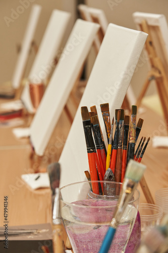 paint brushes and white canvases on easels