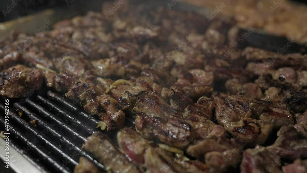 Chef is flipping meat on grill. Barbecue meat preparing on grill, close up. Mutton or pork grilling. A lot of meat at the food festival. Chef is flipping meat on grill. Barbecue meat preparing on grill, close up. Mutton or pork grilling. A lot of meat at the food festival.