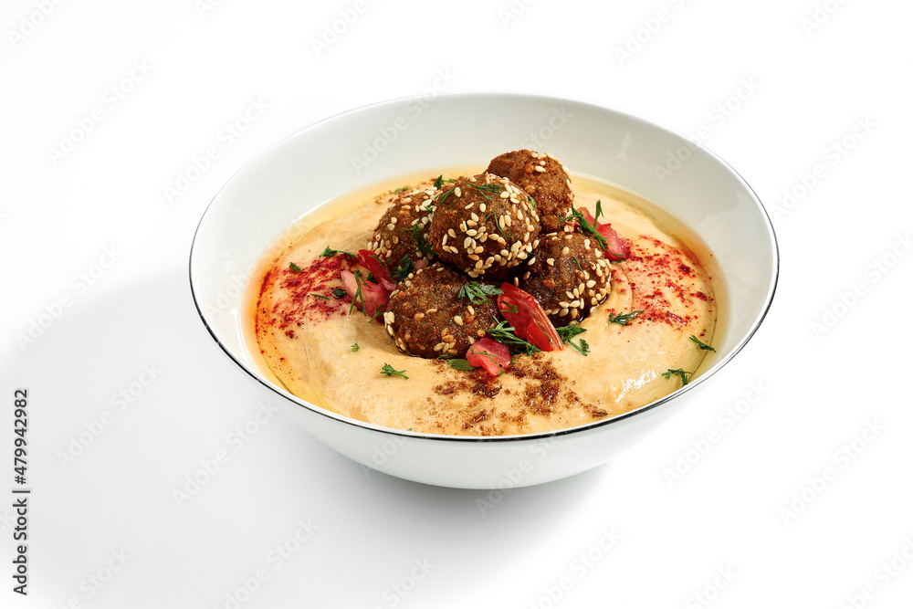 Hummus with olive oil, tomatoes and specials in a bowl on a white plate. Photo for the menu. Isolated Hummus with olive oil, tomatoes and specials in a bowl on a white plate. Photo for the menu. Isolated