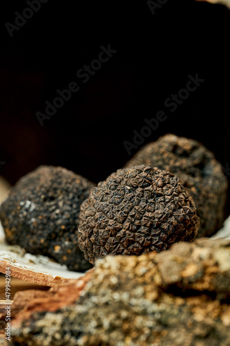 A whole black truffle on bark. Selective focus, close-up. Noise grain in post-production