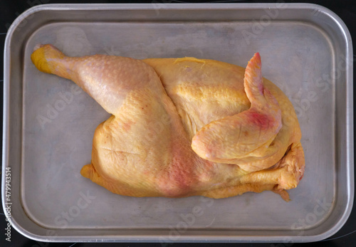 Halved uncooked chicken laid in a roasting tin rady for the oven