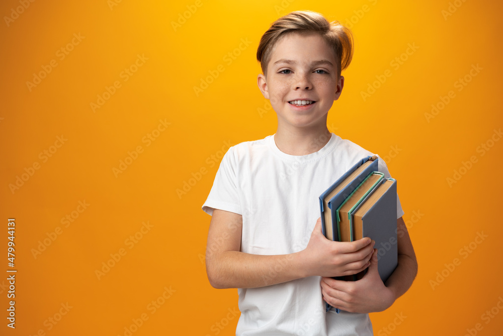 Little schoolboy holding a book against yellow background Little schoolboy holding a book against yellow background