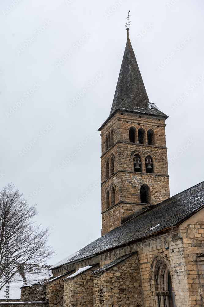 Romanesque church tower in a village. Winter photography with snowy landscape.
