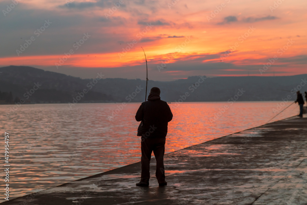 fisherman fishes on Bosphorus Istanbul on a Foggy sunrise. Rainy clouds and dark weather