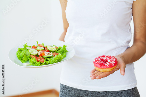 Dieting concept  beautiful young woman choosing between healthy food and junk food.