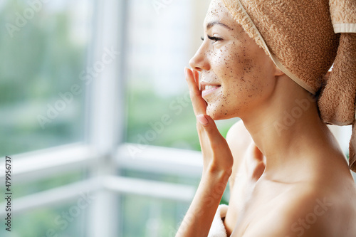Beautiful young woman with scrub mask in spa salon