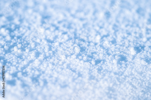 Snow with melted ice crystals and soft blue shadows on a sunny winter day. Background. Selective focus