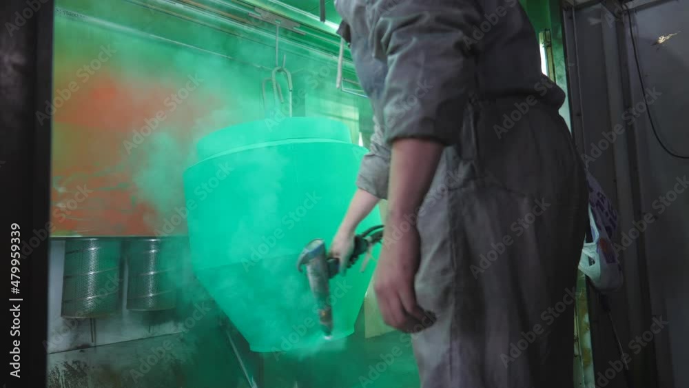 Worker sprays paint to metal part from aerosol gun in the painting chamber. Technician in safety wear work at industrial manufacture. Master paint detail in specialised workshop. Close up Slow motion Worker sprays paint to metal part from aerosol gun in the painting chamber. Technician in safety wear work at industrial manufacture. Master paint detail in specialised workshop. Close up Slow motion
