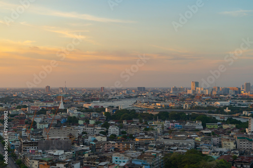 Aerial view of White Prayoon Pagoda, Memorial Bridge, and Phra Pok Klao Bridge with buildings and curve of Chao Phraya River at sunset. Urban city, Downtown Bangkok, Thailand.