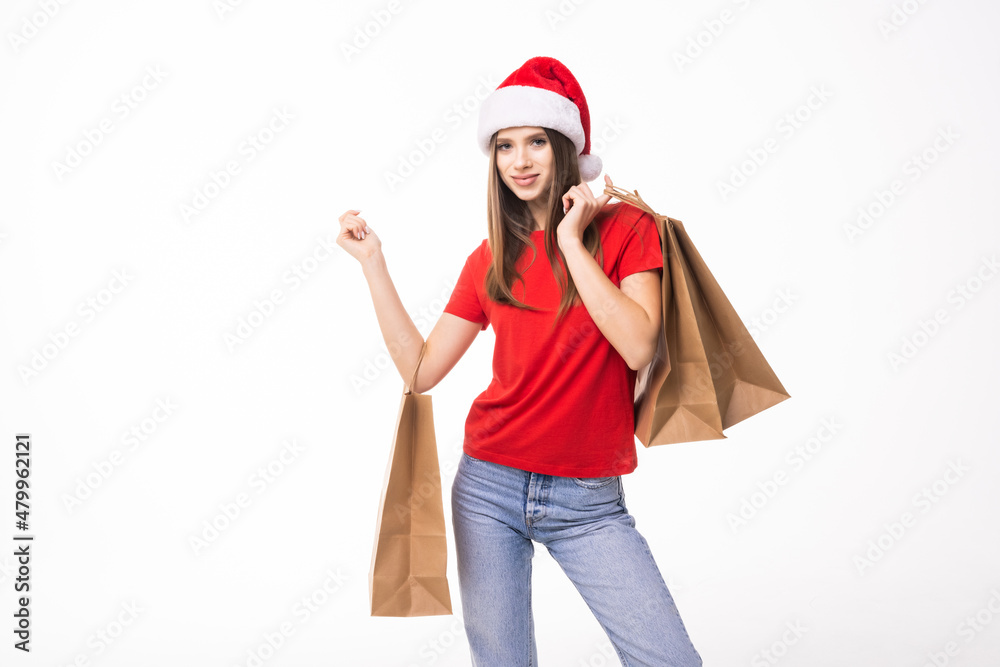 Christmas shopping woman holding shopping bags with gifts. Happy and smiling wearing red santa hat isolated on white background.