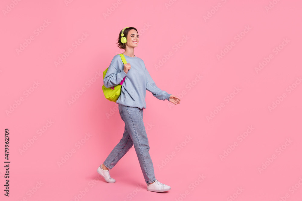 Full size photo of pretty young lady go wear pullover jeans shoes headphones bag isolated on pink background Full size photo of pretty young lady go wear pullover jeans shoes headphones bag isolated on pink background