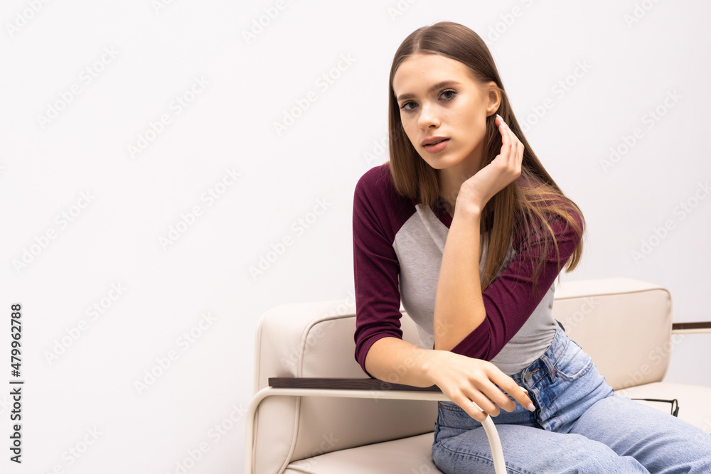 Obraz premium Young pretty woman sitting on her white sofa