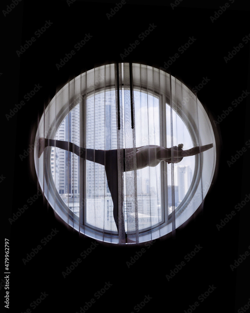 Silhouette of woman doing yoga in the round window Silhouette of woman doing yoga in the round window