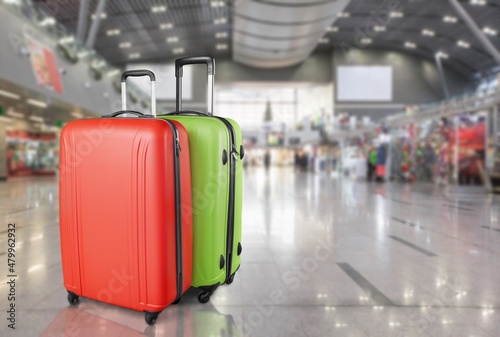 Modern stylish suitcases standing in empty airport hall, unrecognizable traveller's luggage