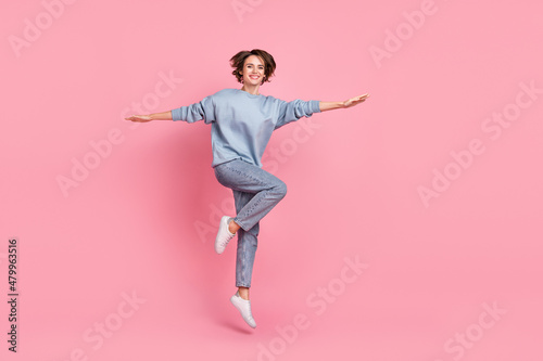 Full size photo of funny young lady jump wear jumper jeans sneakers isolated on pink background