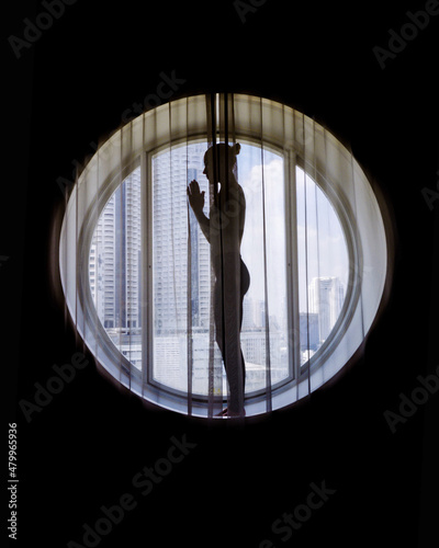 Silhouette of woman meditating in the round window © sashapritchard