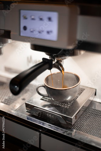The coffee machine pours coffee in the cup, vertical view. Great picture for baner or menu