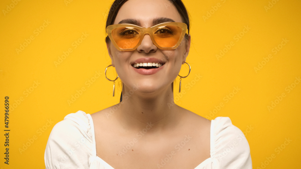 Positive woman in sunglasses looking at camera isolated on yellow. Positive woman in sunglasses looking at camera isolated on yellow.
