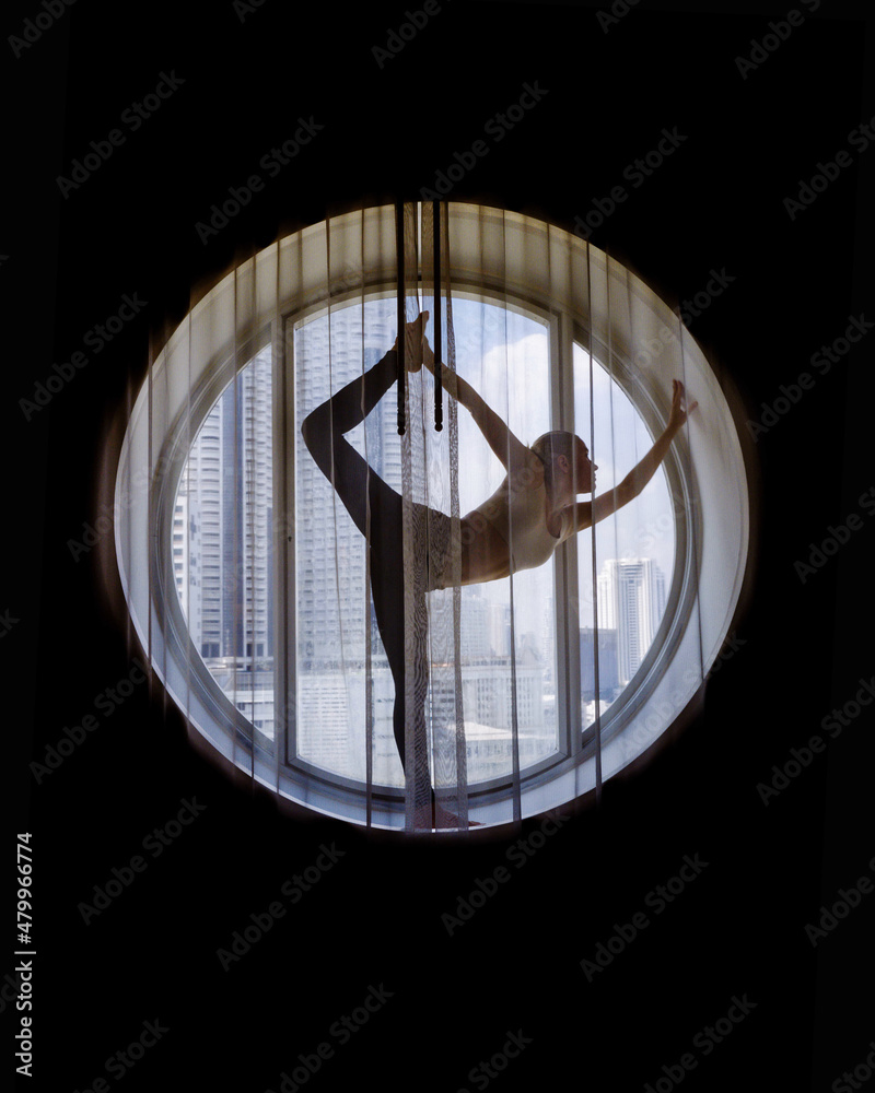 Silhouette of woman doing yoga in the round window