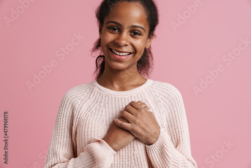 Brunette black girl smiling while holding hands on her chest
