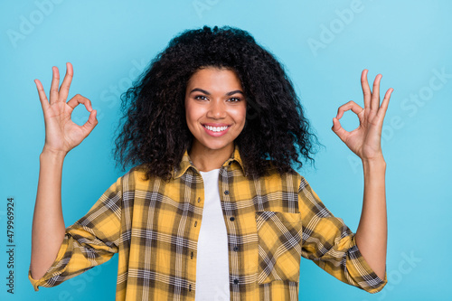 Photo of positive lady show okey sign approve symbol wear checkered shirt isolated blue color background