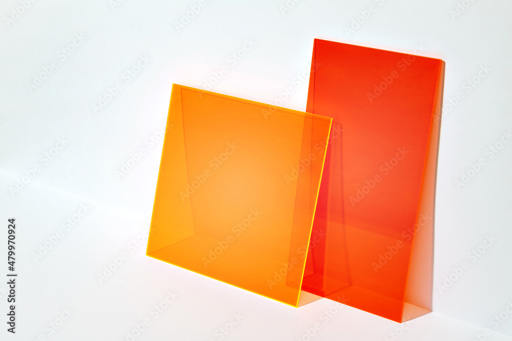 Red and orange acrylic shapes on a bright lit white background. Colourful minimalist stage for advertising, promoting, exhibition new products. Stylish abstract backdrop with space for text.  - obrazy, fototapety, plakaty 