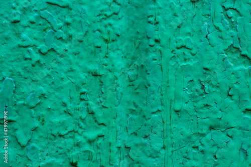 Green old cracked surface as background. Selective focus. Defocus. Colored cracked texture.