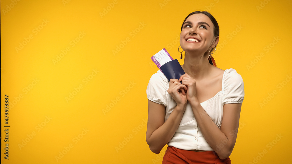 Pleased tourist holding passport and air ticket isolated on yellow. Pleased tourist holding passport and air ticket isolated on yellow.