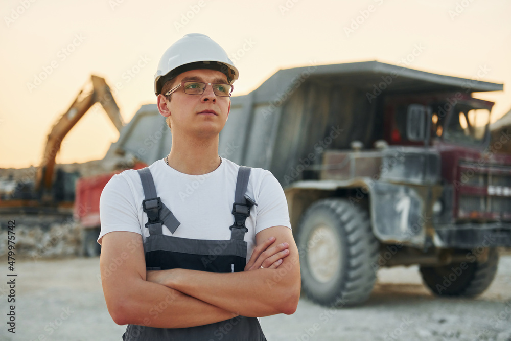 Fototapeta premium Near loading vehicle. Worker in professional uniform is on the borrow pit at daytime