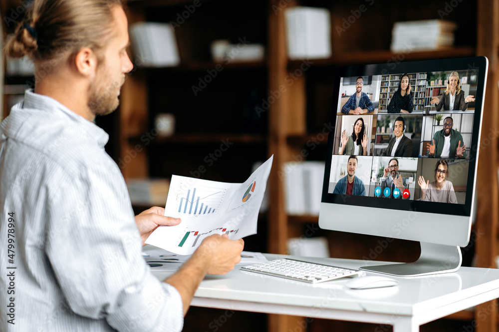 Virtual business meeting, online discuss. Side view of a corporate employee communicating with a group of multi-ethnic colleagues via video call, analyzing financial statements, planning strategy