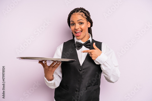 afro black woman looking excited and surprised pointing to the side. waiter with a tray